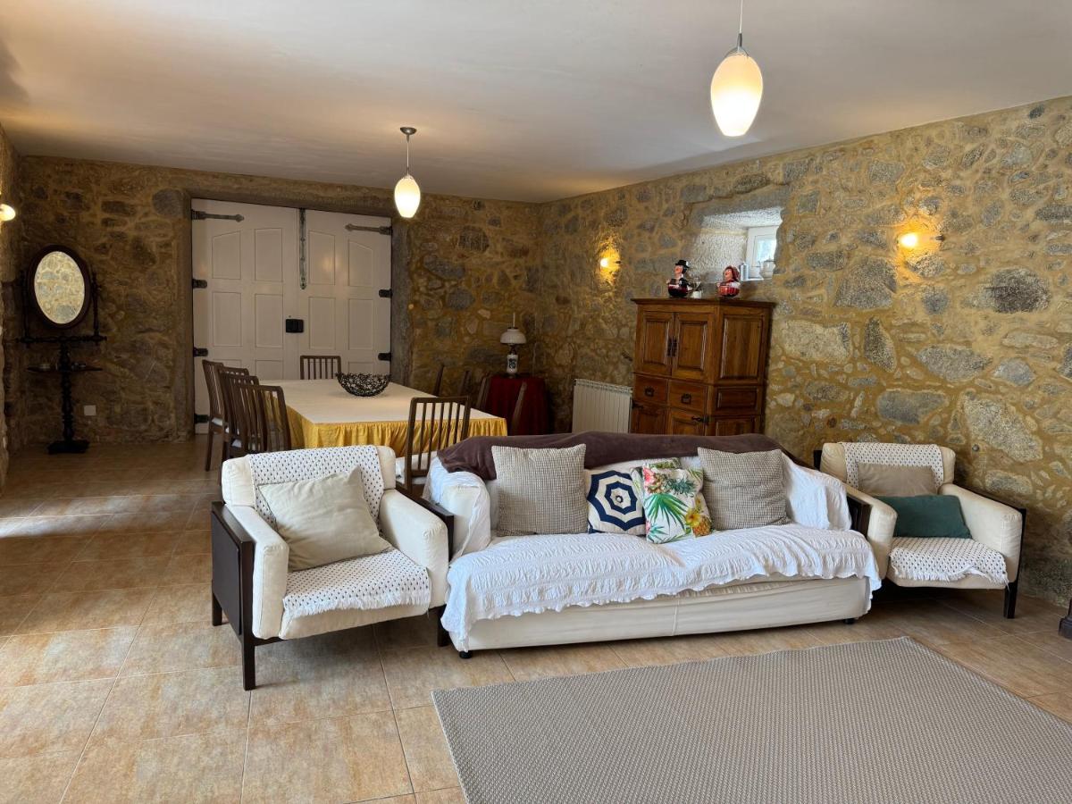 Sala de estar com sofá branco, poltronas e paredes em pedra à vista
